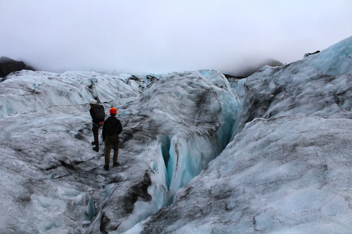 Zwei Wanderer mit Helm auf einer geführten Gletscherwanderung in Island zwischen Eisspalten
