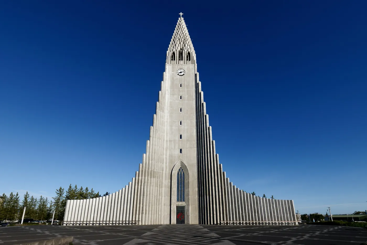 Hallgrímskirkja in Reykjavík von außen: der 73 Meter hohe Turm mit den gestaffelten Seitenflügeln vor tiefblauem Himmel