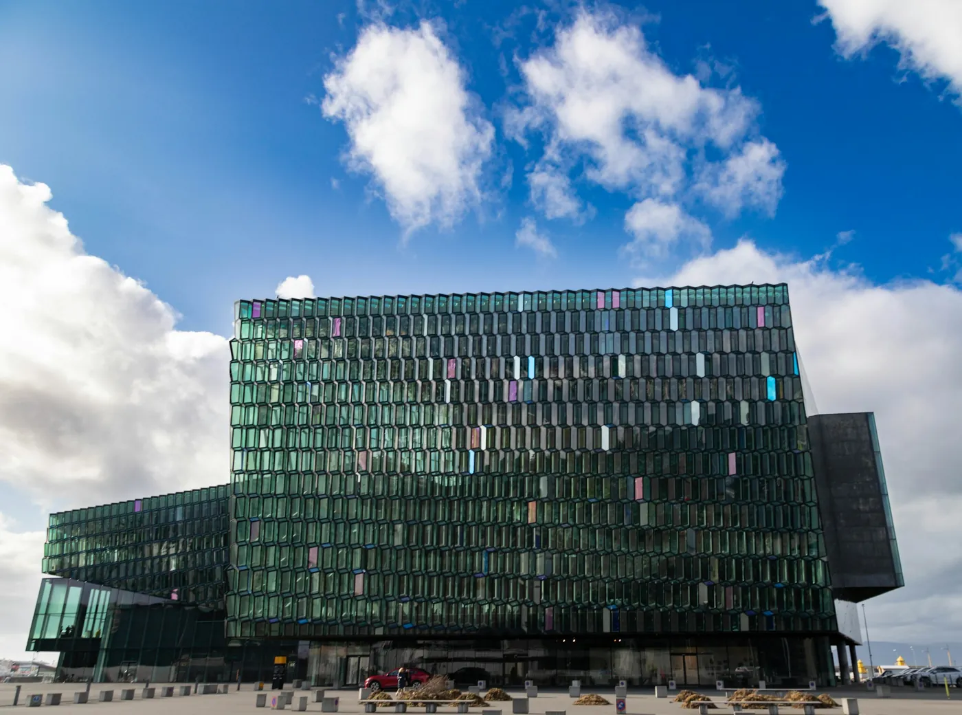 Konzerthaus Harpa am Hafen von Reykjavík mit seiner grün schimmernden Glasfassade unter blauem Himmel