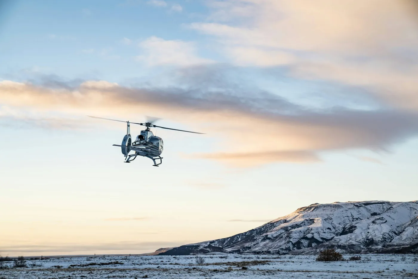 Helikopter im Flug über verschneiter Landschaft in Island