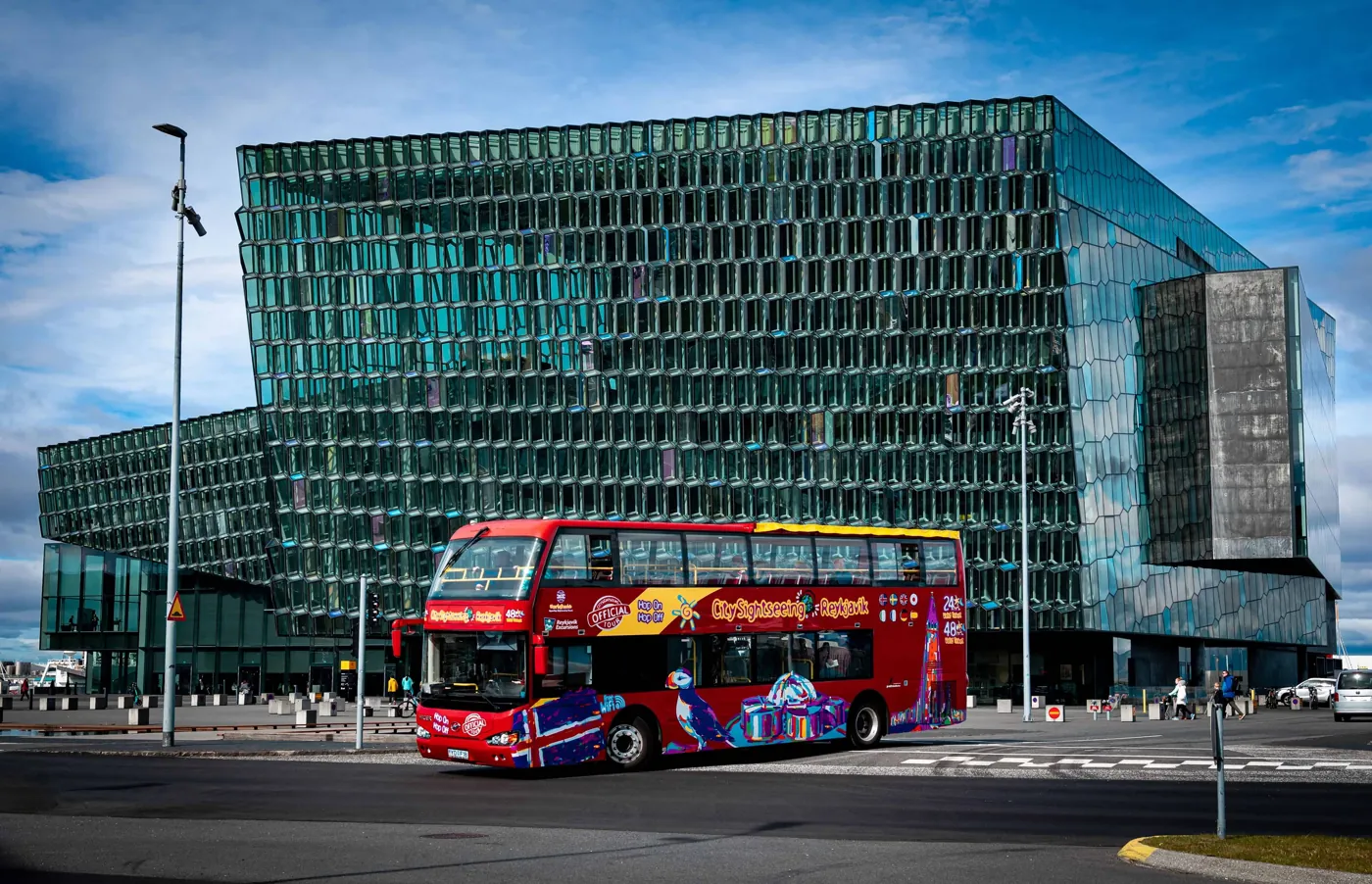 Roter Hop-on-Hop-off-Bus vor dem Konzerthaus Harpa in Reykjavík