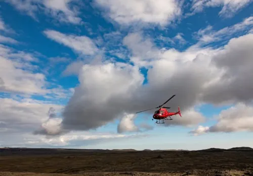 Roter Helikopter in der Luft über Island