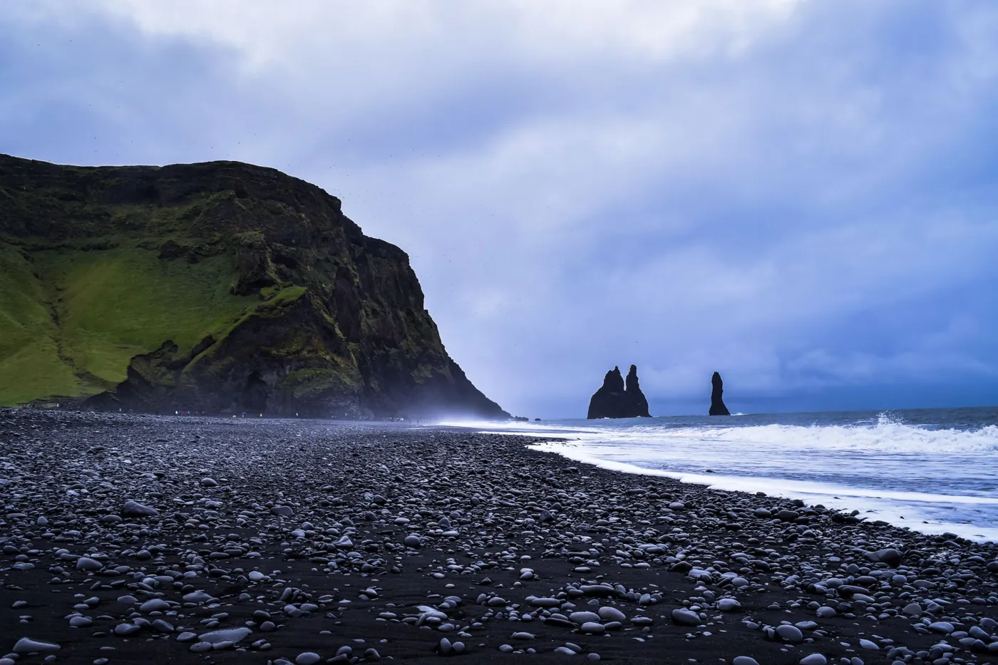 Brandung am schwarzen Strand bei Vík, im Hintergrund die Felsnadeln Reynisdrangar