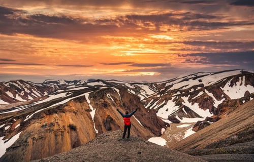 Wandererin auf dem Gipfel mit vulkanischem Gebirge in Landmannalaugar, Island