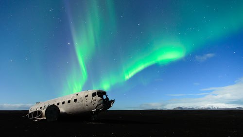 Nordlichter tanzen über verlassenes Flugzeug am südisländischen Strand in der Nähe von Vik